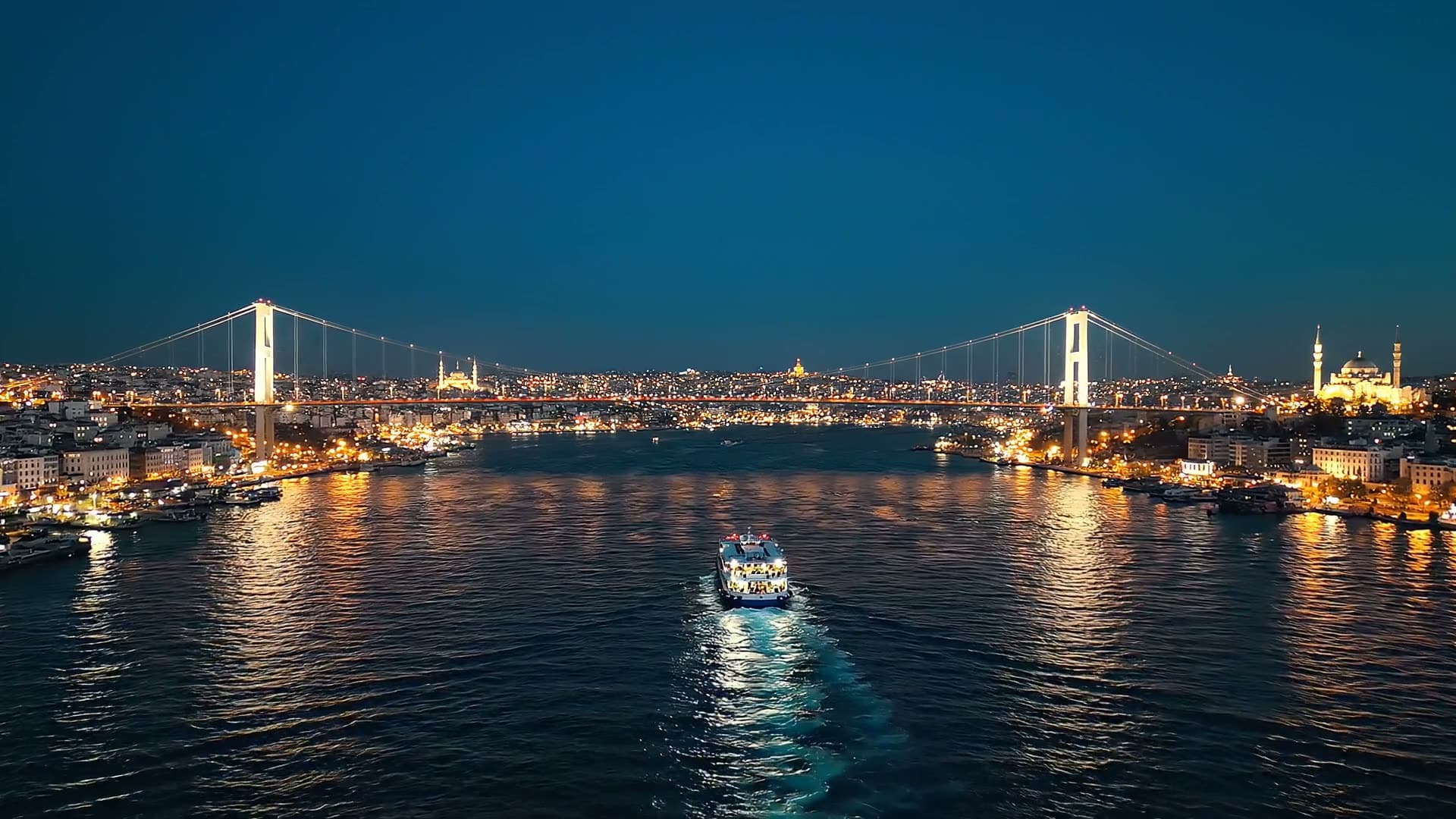 Mavi saatte İstanbul Boğazı'nın üzerinden sinematik havadan çekim: köprünün ışıkları yanıyor, bir vapur… Google Veo 3.1 Lite ile üretilen videodan bir kare.