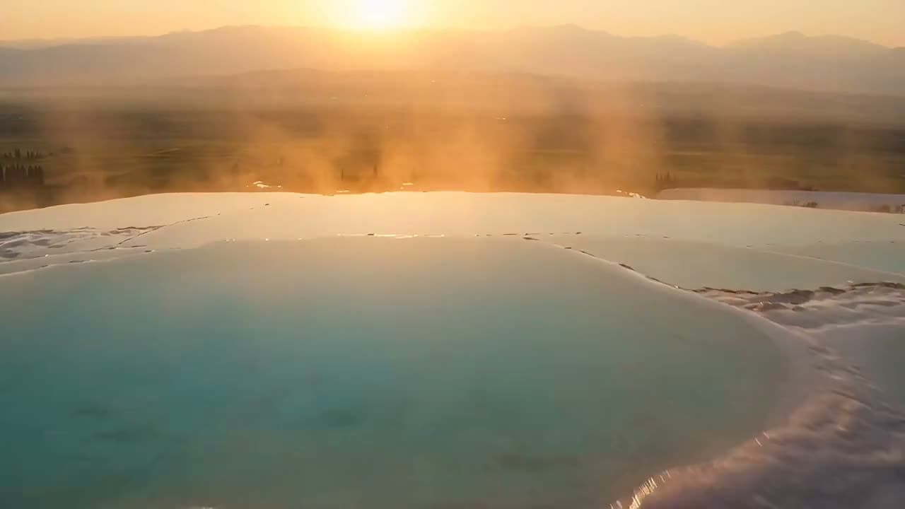Pamukkale'de gün batımında travertenlerin üzerinden sinematik dron çekimi: bembeyaz teraslar, turkuaz… Seedance 2.5 ile üretilen videodan bir kare.
